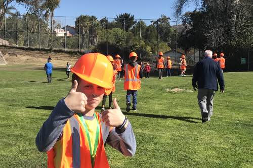 SWPPP Intern gives the camera double thumbs up as they tour the site of their future bioswale with contractors bidding on the project